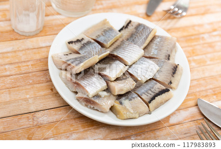 Salted pickled herring fish served on a ceramic plate 117983893