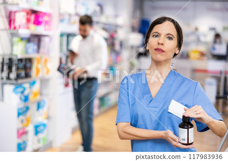 Female druggist presenting medicine in drugstore 117983936