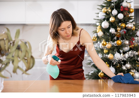 Young woman wipes the table with a damp cloth 117983943