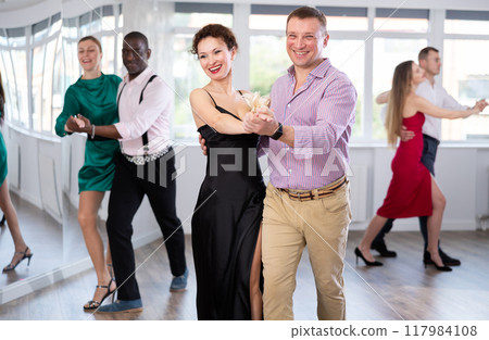 Middle-aged man and woman practicing waltz in dancing studio Middle-aged man and woman practicing waltz in dancing studio 117984108