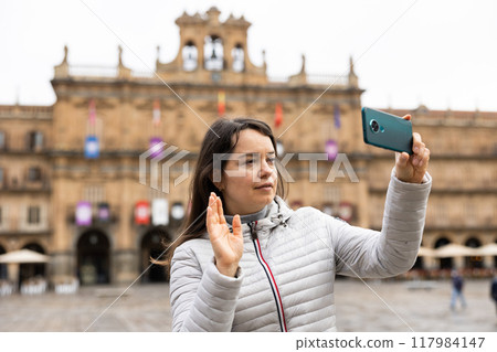 Woman is taking photos on her camera while journey through the Plaza Mayor. Spain Woman is taking photos on her camera while journey through the Plaza Mayor. Spain 117984147