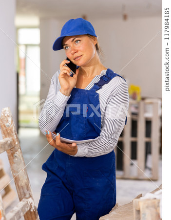 Young woman engineer in uniform is talking on a mobile phone 117984185
