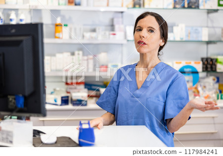 Female pharmacist standing behind counter in drugstore Female pharmacist standing behind counter in drugstore 117984241
