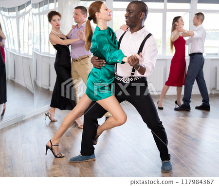 Woman dances incendiary tango with African man partner during choreography lesson 117984367
