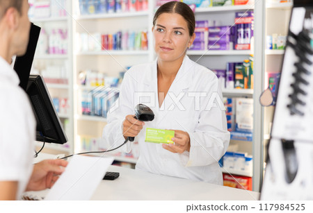 Girl pharmacist near cash register area serves customer, scans product and selling drugs Girl pharmacist near cash register area serves customer, scans product and selling drugs 117984525