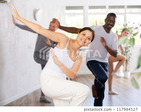 Active men and women of different ages practicing Hip-hop dance in training hall during dancing classes Active men and women of different ages practicing Hip-hop dance in training hall during dancing classes 117984527