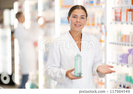 Young female pharmacist offering shampoo Young female pharmacist offering shampoo 117984549