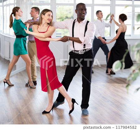 Woman with African man dancing waltz in couple during lesson at studio Woman with African man dancing waltz in couple during lesson at studio 117984582