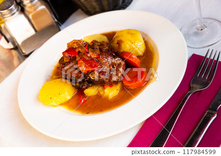 Baked lamb shoulder with vegetables 117984599
