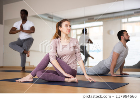 Woman sitting in lord of the fishes pose, group training Woman sitting in lord of the fishes pose, group training 117984666