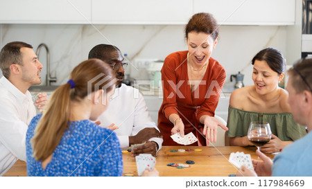 Joyful middle-aged men and women playing poker at home 117984669