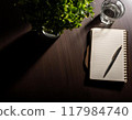 A notebook and a glass of water on a desk 117984740