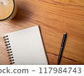 An open notebook on a table with a coffee latte 117984743