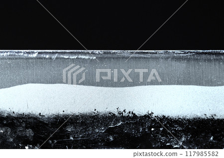 A stock image of a traditional Japanese bronze blacksmith's blade, its cutting edge and edge boundary, and striped pattern photographed horizontally against a blue glow and black background. 117985582
