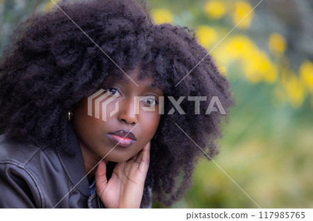 A stunning young woman with a natural afro hairstyle posing beautifully in an outdoor setting 117985765