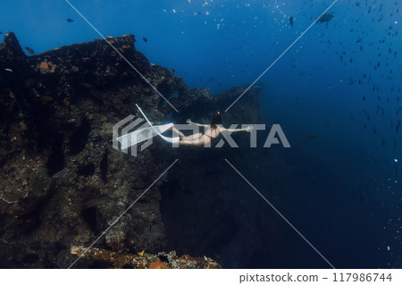 Sporty female freediver swims underwater and explores old wreck ship in Tulamben, Bali. 117986744
