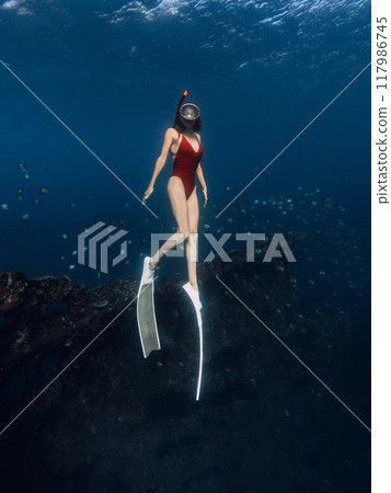 Woman free diver dives in blue ocean on wreck ship in Bali. 117986745