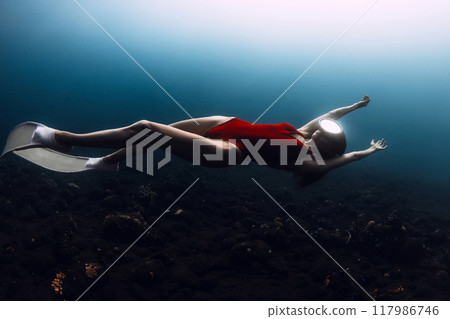 Sexy woman freedives. Young sporty female freediver swims underwater in deep ocean 117986746