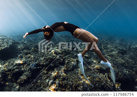 Freediver woman posing over coral reef with sun rays in tropical ocean 117986754