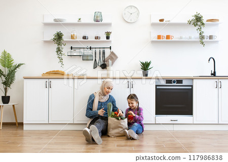 Muslim mother and daughter preparing healthy food together in kitchen Muslim mother and daughter preparing healthy food together in kitchen 117986838
