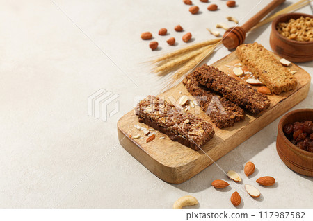 Granola bars on a wooden board with ears of corn and nuts Granola bars on a wooden board with ears of corn and nuts 117987582