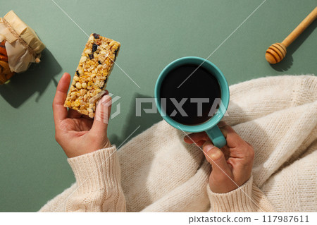 Granola bar with cup of tea in female hands Granola bar with cup of tea in female hands 117987611