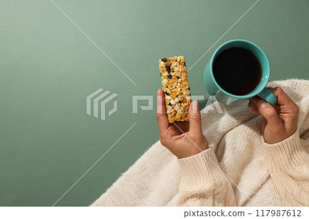 Granola bar with cup of tea in female hands Granola bar with cup of tea in female hands 117987612