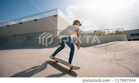 Skateboarder skateboarding at skatepark in city Skateboarder skateboarding at skatepark in city 117987844