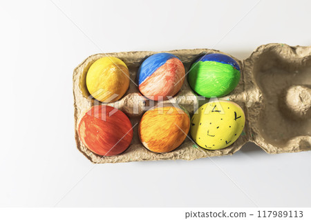 Colorful easter eggs in a cardboard box on a white background. Colorful easter eggs in a cardboard box on a white background. 117989113