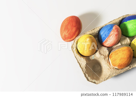 Colorful Easter eggs in a cardboard box on a white background. Colorful Easter eggs in a cardboard box on a white background. 117989114
