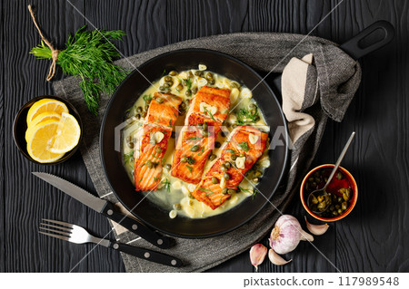 salmon piccata with lemon caper sauce in a pan 117989548