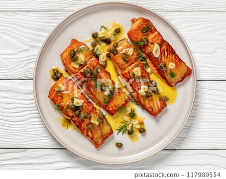 salmon piccata with lemon caper sauce on plate 117989554