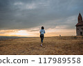 Woman Jogging by Historic Church at Sunset in Scenic Countryside 117989558