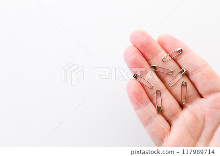 Hand holding safety pins. 117989714