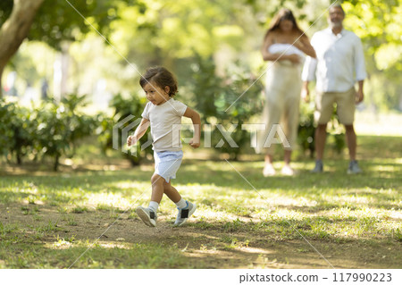 Little boy running happily in the park while parents watching in background 117990223