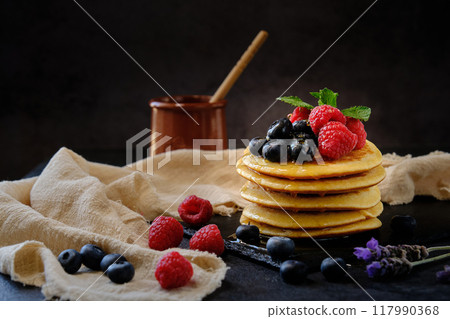 pancakes with berries and honey on dark background pancakes with berries and honey on dark background 117990368