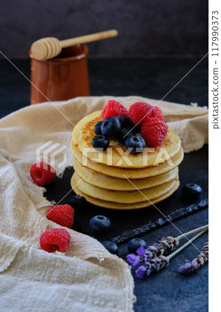 pancakes with berries and honey on dark background 117990373