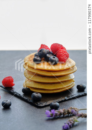 pancakes with berries and honey on dark background 117990374