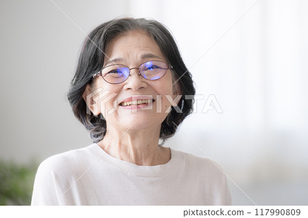 Smiling senior woman. Close-up of a healthy elderly woman laughing out loud in a room, looking at the camera 117990809