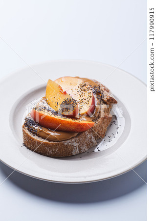 Peanut butter toast with peach and seeds. 117990915