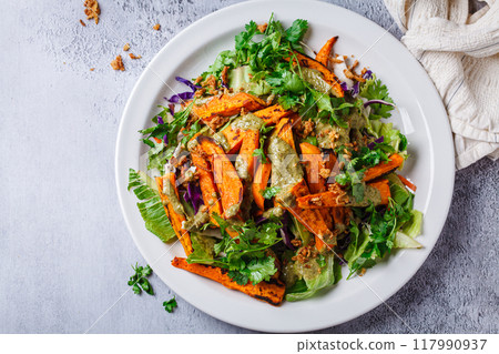 Roasted sweet potato wedges salad with pesto tahini dressing. 117990937