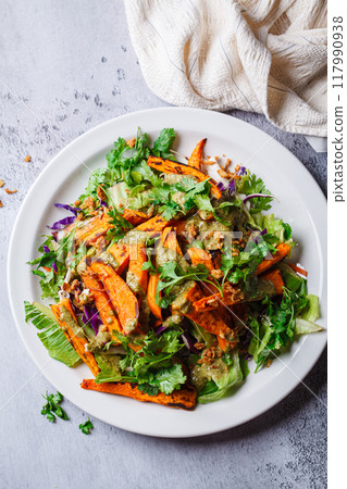Roasted sweet potato wedges salad with pesto tahini dressing. Roasted sweet potato wedges salad with pesto tahini dressing. 117990938