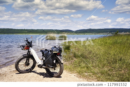 Electric fat bike on the sandy beach of a former lignite mining area flooded with groundwater 117991532