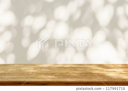 Empty wood table top on beige wall texture with tree leaves shadow background 117991718