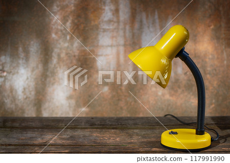 A table lamp on old boards against a shabby background A table lamp on old boards against a shabby background 117991990