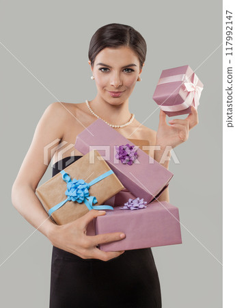 Elegant glamorous young woman holds beautiful gift box in hands and looks on the camera Elegant glamorous young woman holds beautiful gift box in hands and looks on the camera 117992147