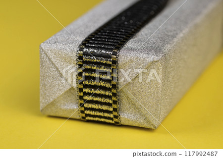 with a black and silver ribbon tied with a silver gift package 117992487