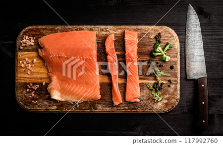 Slised salmon on wooden board with knife 117992760