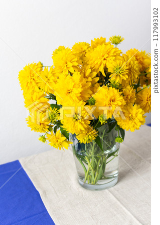 A summer bouquet of yellow Rudbeckia Goldquelle flowers brings vibrant color to home decoration, showcasing a seasonal and cheerful floral arrangement 117993102