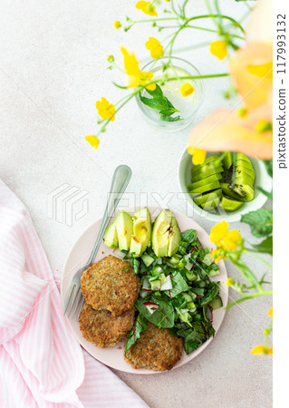 Quinoa cutlets and mixed salad with avocado and radishes, kiwi and water Quinoa cutlets and mixed salad with avocado and radishes, kiwi and water 117993132